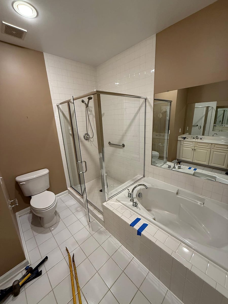 Before: the old bathroom with a tiled tub deck and framed shower