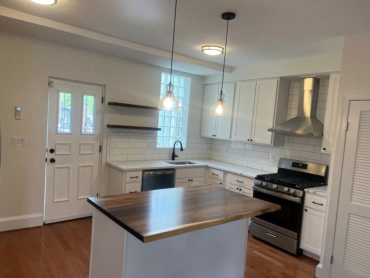 White kitchen with a wood-top island, subway tile and floating shelves